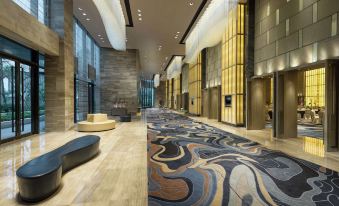 In the middle of the lobby, there are couches and tables, with an empty room next to it at Hilton Shenzhen Shekou Nanhai