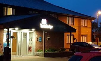 an exterior view of a hotel building at night , with the hotel 's name displayed prominently at Travelodge Carlisle Todhills