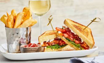 a white plate with a sandwich , fries , and a glass of wine on a dining table at Courtyard Baltimore Hunt Valley