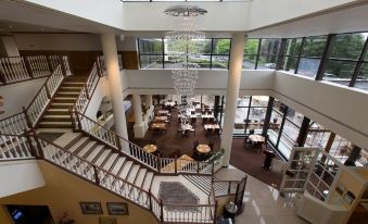 a large , elegant hotel lobby with multiple floors , featuring a staircase , chandeliers , and numerous potted plants at Holiday Inn Clinton - Bridgewater