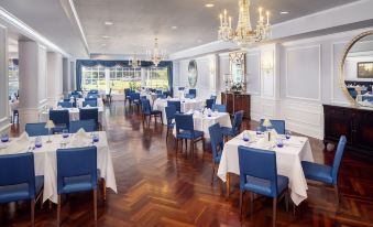 a large , elegant dining room with multiple tables set for a formal dinner , featuring blue chairs and white tablecloths at Historic Boone Tavern