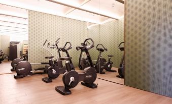 There is a gym with multiple exercise bikes and a large mirror in the center of the room for exercising at Blossom House Shanghai On The Bund