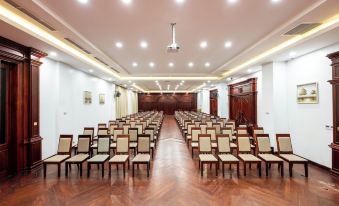 a large , empty conference room with rows of chairs arranged in a symmetrical pattern , under white lights from overhead overhead lights at Lbn Asian Hotel