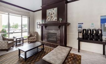 a living room with a fireplace , couches , and tables , along with a painting on the wall at Best Western High Road Inn