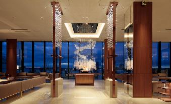 a large , modern hotel lobby with high ceilings and a view of the ocean outside at Candeo Hotels Omiya