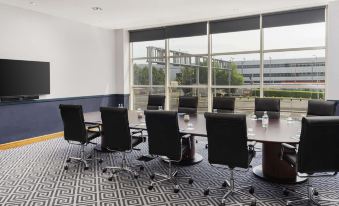 a large conference room with a long table , chairs , and windows looking out onto a cityscape at Sofitel London Gatwick