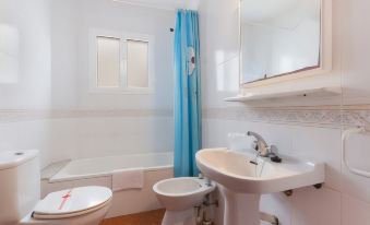 a small bathroom with white walls , a bathtub , a sink , and a toilet , along with blue curtains at Sol Y Mar