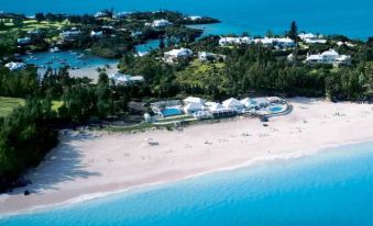 aerial view of a beautiful beach with white buildings and umbrellas , surrounded by clear blue water at Rosewood Bermuda