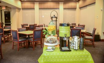 a table in a room with a green tablecloth has a coffee maker and a yellow sign at Hilton Garden Inn Lexington/Georgetown