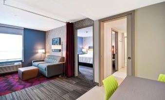 a hotel room with a living area , bedroom , and dining area , all connected by a sliding door at Home2 Suites by Hilton Walpole Foxboro