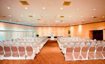 a large , empty banquet hall with rows of white chairs and a podium at the front at Best Western Plus Gran Hotel Morelia