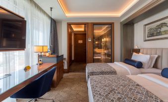 a hotel room with two beds , a desk , and a door leading to a balcony at Golden Tulip Istanbul Bayrampasa