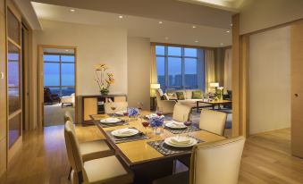 a dining room with a table set for a meal , surrounded by chairs and a large window at Somerset Grand Central Dalian