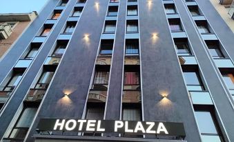 "a large hotel building with a sign that reads "" hotel plaza "" prominently displayed on the side of the building" at Hotel Plaza