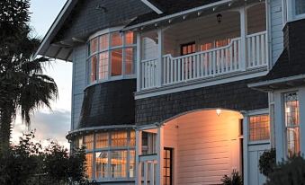 a large house with a white porch and balcony , surrounded by trees and lit up at dusk at Cedar House