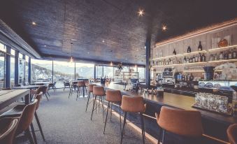 a modern bar with wooden furniture , pendant lights , and a large window offering a view of the city at Spaces Hotel