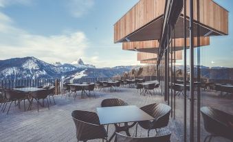 a rooftop patio with tables , chairs , and a view of the mountains in the background at Spaces Hotel