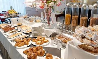 a dining table filled with a variety of pastries , including croissants , bagels , and other baked goods at Cosmopolitan Hotel