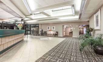 a spacious lobby with high ceilings , white columns , and a large reception desk , surrounded by various pieces of furniture and plants at Gateway Hotel