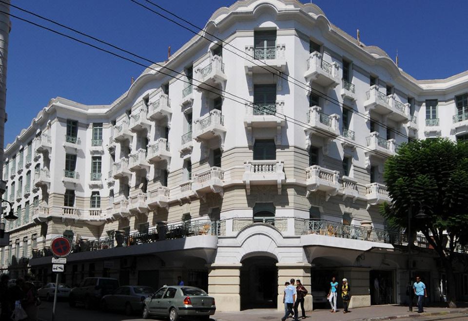 a white building with balconies and people walking on the street in front of it at Majestic Hotel