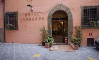 "the entrance of a hotel named "" hotel leonardo "" with an arched doorway and potted plants , set against a red brick building" at Hotel Leonardo
