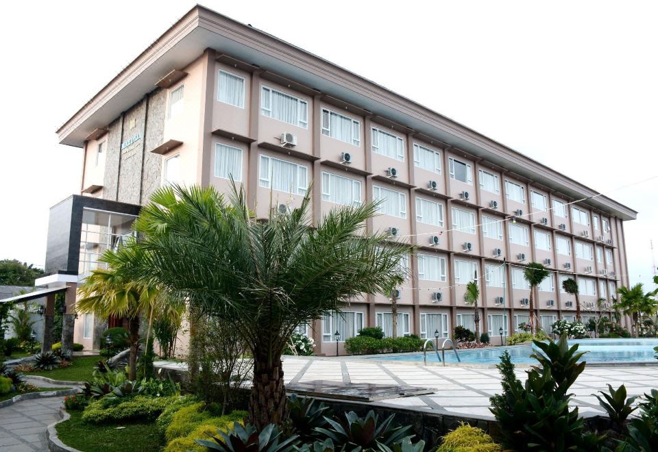 a large hotel building surrounded by lush greenery , with a swimming pool in front of it at Mexolie Hotel