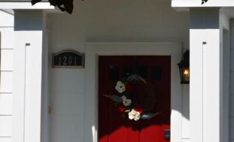 a red door with a wreath on it is at the entrance of a white house at Sassafras Inn