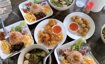 a table is filled with various dishes , including bowls of soup and plates of noodles and vegetables at BaanSuanLeelawadee Resort Amphawa