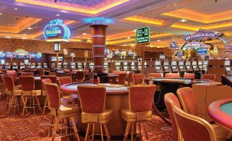 a large , well - lit casino with multiple tables and chairs , as well as slot machines and a neon sign at Blue Chip Casino Hotel and Spa