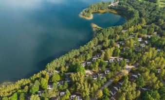 a bird 's eye view of a serene lake surrounded by trees and houses , with a road winding through the landscape at Sunparks Kempense Meren