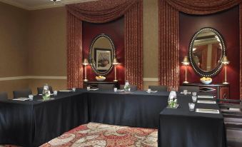 a large conference room with multiple tables and chairs arranged in a semicircle , creating a formal setting at Juniper Hotel Cupertino, Curio Collection by Hilton