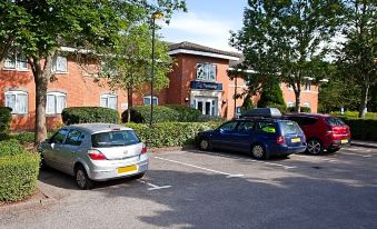 a parking lot with several cars parked in front of a brick building , possibly a hotel at Travelodge Stonehouse