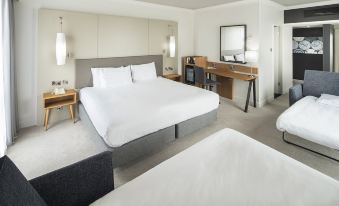 a modern hotel room with a large bed , two nightstands , and a desk , all set against white walls at Crowne Plaza Stratford Upon Avon