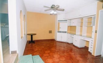 an empty room with white walls and wooden floors , featuring a ceiling fan and several cabinets at La Esperanza