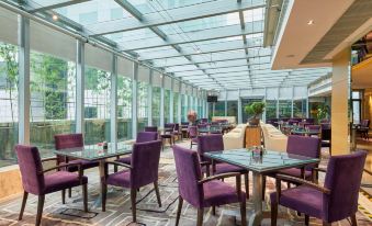 A restaurant with large windows and tables arranged in the center, facing each other at The Westin Bund Center Shanghai