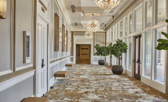 a long , elegant hallway with marble floors and ornate chandeliers , decorated with potted plants and a chandelier at The Grand Hotel Golf Resort & Spa, Autograph Collection