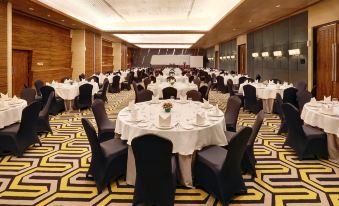 a large banquet hall with round tables and chairs set up for a formal event at Hotel Ciputra Cibubur Managed by Swiss-Belhotel International