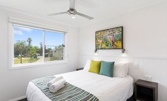 a clean and well - organized bedroom with a large bed , a window , and a painting on the wall at Ingenia Holidays Lake Conjola