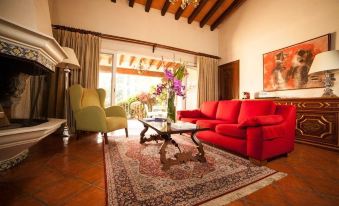 a cozy living room with a red couch , a yellow chair , and a rug on the floor at Las Mananitas Hotel Garden Restaurant and Spa