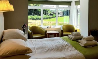 a cozy bedroom with a large bed and a view of the outdoors through a window at The White House Guest House