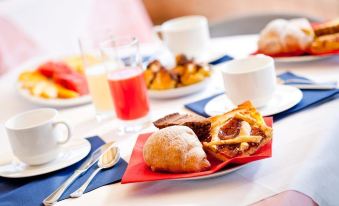 a dining table set with a variety of food items , including pastries , fruits , and beverages at Hotel Florence