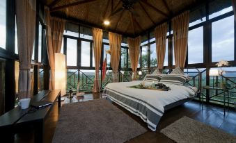 a spacious bedroom with a large bed , a ceiling fan , and a view of the ocean at Bilut Hills @ Bentong