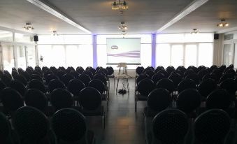 a conference room with rows of chairs arranged in a semicircle , and a projector screen on the wall at La Cote d'Or