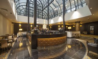 a modern hotel lobby with a curved reception desk and a large glass ceiling overhead at President Hotel