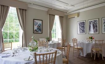 a dining room with several tables and chairs set up for a formal meal , creating a pleasant atmosphere at Eastwood Hall