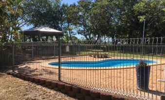 a backyard with a swimming pool surrounded by a chain link fence , and a picnic table in the background at Hillview Motel