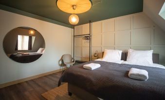 a large bed with a wooden headboard and footboard is in the center of a room with white walls , a chair , and a round at Mr Lewis Haarlem