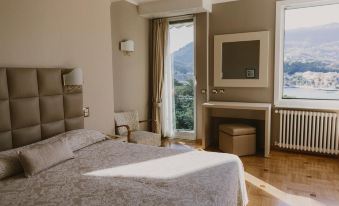 a bedroom with a large window , wooden floor , and a bed covered in a white comforter at Hotel Metropole