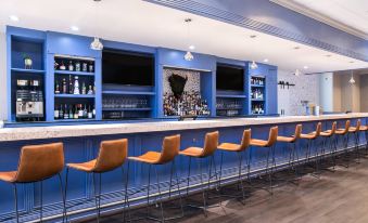 a modern bar with blue walls and wooden floors , featuring a variety of seating options and a tv screen at Winston-Salem Marriott