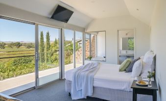 a large bedroom with a white bed and sliding glass doors leading to an outdoor patio at Barossa Shiraz Estate